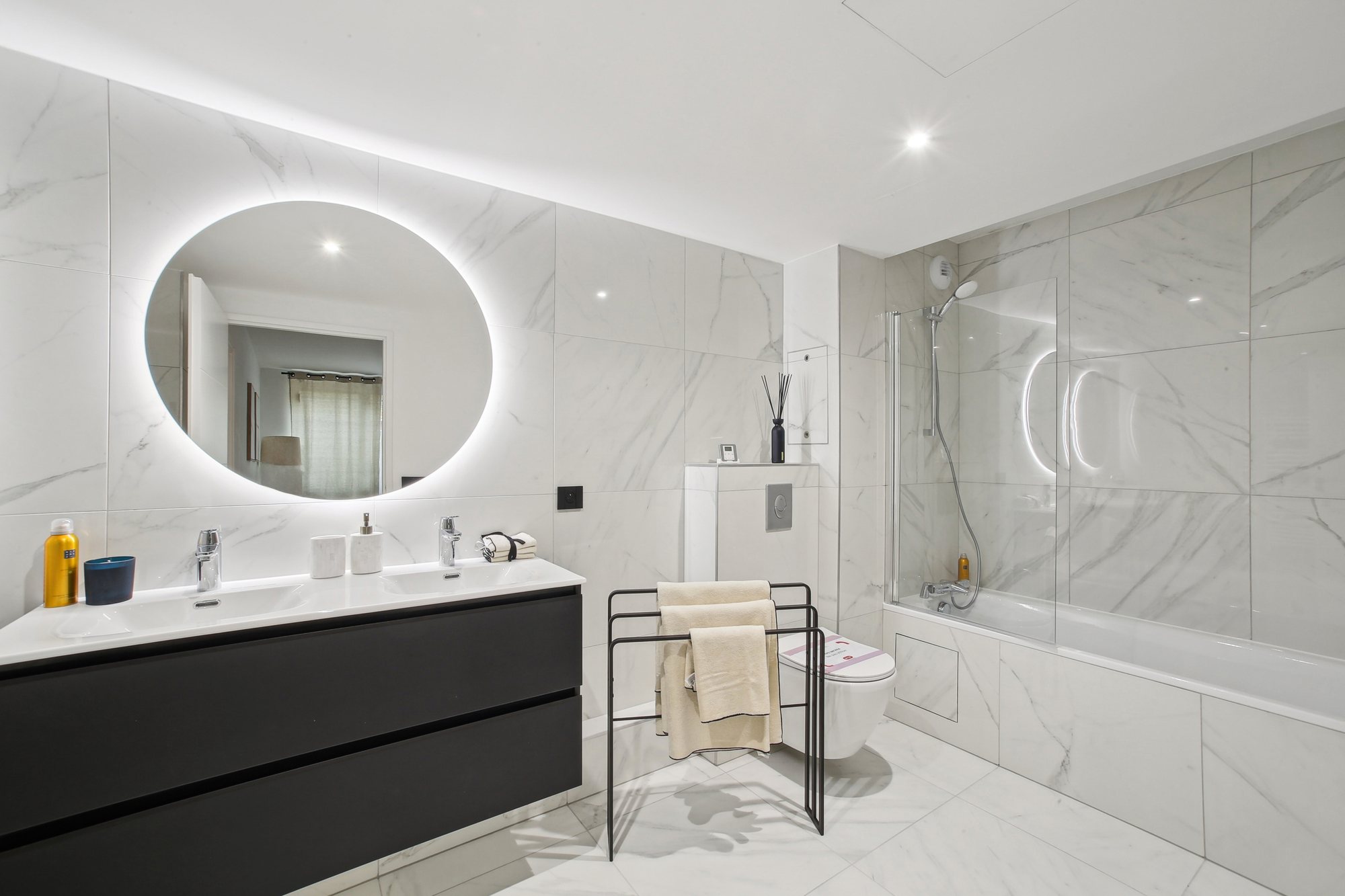 Salle de bains décorée avec miroir circulaire et baignoire